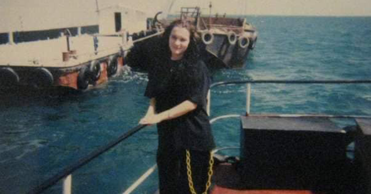 Colleen pictured with her second ship, the USS Cimarron, in the background.