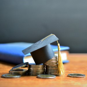 graduation cap on top of coins