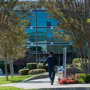 Photo of male employee walking towards corporate building